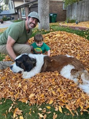 Andrew Stein enjoying the Fall leaves with his son and dog